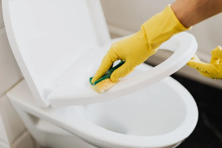 services-03 a-woman-in-a-green-shirt-and-black-gloves-vacuuming-a-gray-ottoman-5txz228u4eo